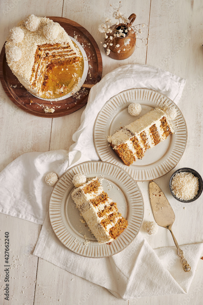 Poster Vertical shot of two plates and a wooden tray with slices of a white coconut flake cake