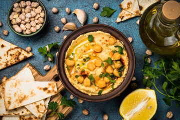 Hummus with olive oil and pita at kitchen table.