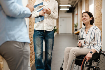 Young three colleagues smiling and talking while standing in office