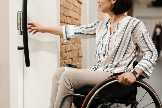White young woman in wheelchair opening door at office