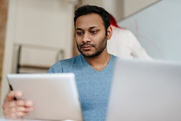Middle eastern man working with tablet computer while sitting at desk