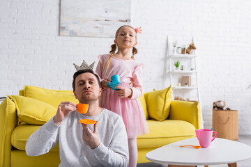 dad and daughter holding toy cups while playing prince and princess at home © LIGHTFIELD STUDIOS