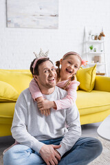 excited girl embracing happy father while playing prince and princess at home