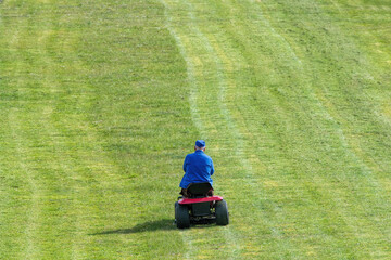 man in blue mowing a lawn