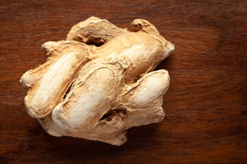 Fototapeta premium Macro close-up of Organic dry Ginger root (Zingiber officinale) or sonth on wooden top background. Pile of Indian Aromatic Spice. Top view