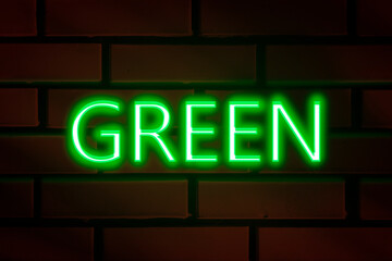 Neon lettering - GREEN on a red brick wall.