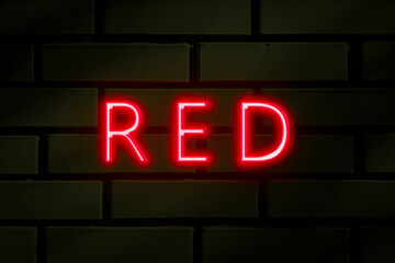 Neon inscription -Red on a green brick wall.
