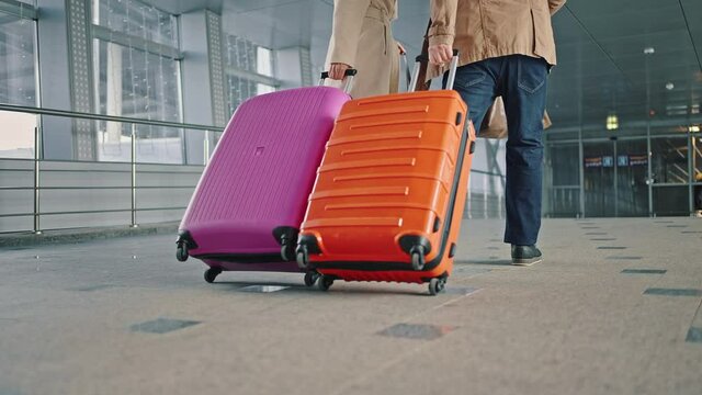 Hurry to flight. Two travellers late for flight, start running down airport terminal with luggage, close up of suitcases