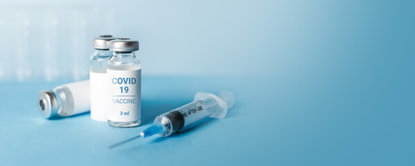 Coronavirus vaccine banner. Ampoules with coronavirus vaccine and a syringe on blue background. Covid-19 treatment