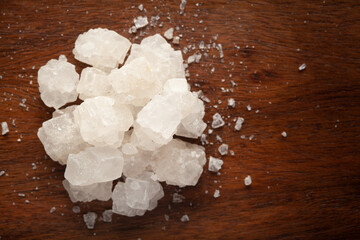 Close-up of coarse sea Salt (sodium chloride) edible on wooden top background.