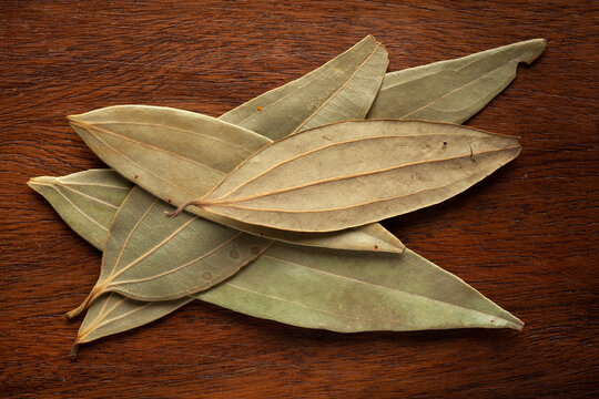 Macro close-up of Organic Indian bay leaf (Cinnamomum tamala)  Tez Patta on wooden top background. Pile of Indian Aromatic Spice. Top view