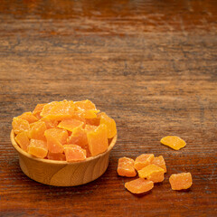 dried mango fruit diced - small wooden bowl on a weathered wood background