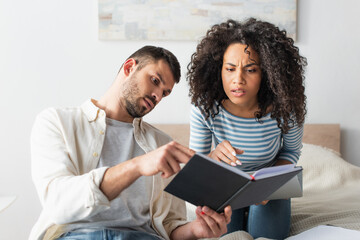 Obraz premium interracial couple looking at notebook in bedroom