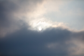 The sun shines behind the clouds during