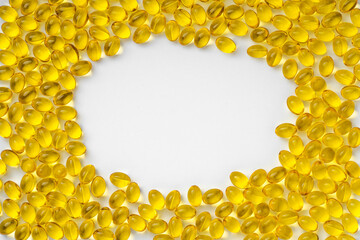 Yellow transparent pills on a white background with a copy space in the center, in the form of a frame. Pills with vitamin D3.