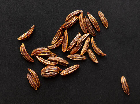 Close up of cumin seeds on a black background.