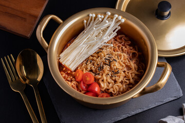 Spicy Korean instant noodles sprinkle with seaweed in a brass pot. Close-up.