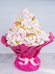 Sweet bouquet of Marshmallows sweets, beautifully decorated, lies on a gray background. There is a place for text.Holiday concept, congratulations.