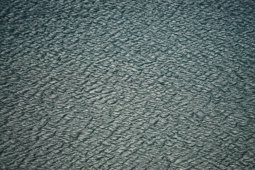 Texture of dark green calm water of lake. Meditative ripples on water surface. Nature minimal background of deep green lake. Natural backdrop of clear dark turquoise water. Full frame of lake fragment