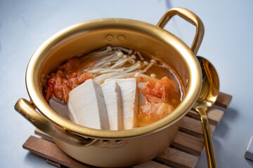 Kimchi soup with needle mushroom with tofu in a bowl on a white background, Korean food (Kimchi Jjigae)