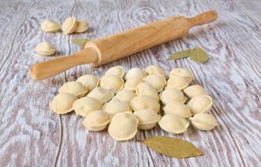Frozen dumplings and wooden rolling pin on a wooden table, close up
