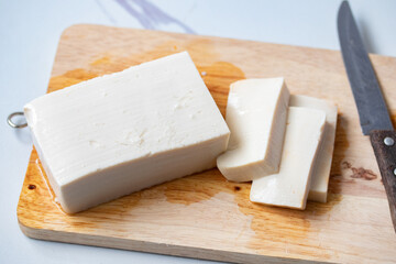 White square tofu cubes On a wooden cutting board and a knife