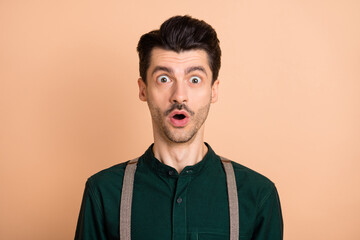 Obraz premium Photo of excited crazy guy open mouth look camera wear green shirt suspenders isolated beige background