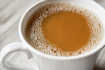 top view of a white cup of coffee with cream, horizontal orientation
