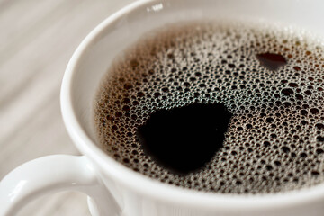 black coffee in a white cup on wooden surface, horizontal orientation