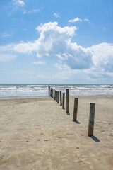 Poles in the beach with ocean and blue sky background
