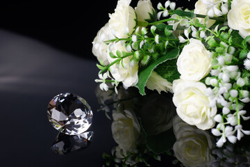 Excellent diamond of the first water and bouquet of white roses with reflection on black mirror background close up view. Jewelry diamonds sale, invitation, action, discount banner, poster template
