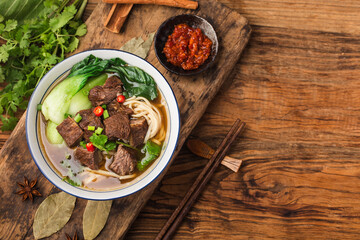Spicy red soup beef noodle in a bowl on wooden table