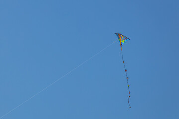 Fototapeta na wymiar One kite with tail in the blue sky