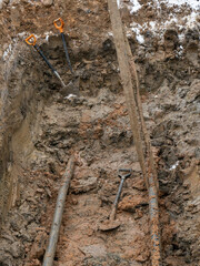 a hole dug in the clay soil for laying underground utilities. Work on digging the earth for laying pipes