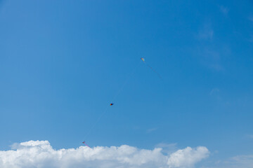 Three kites in the blue sky with white clouds