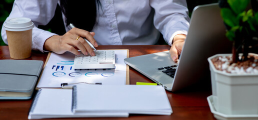 Close up businesswoman hand using calculator and working with laptop calculate about finance accounting at coffee shop outdor.finance data analysis accounting concept.