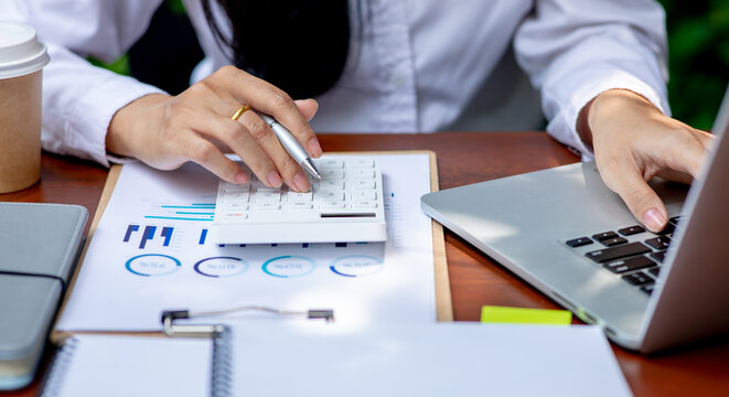 Close up businesswoman hand using calculator and working with laptop calculate about finance accounting at coffee shop outdor.finance data analysis accounting concept.