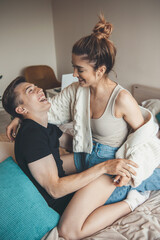 Caucasian loving couple are playing in bed embracing and smiling at each other