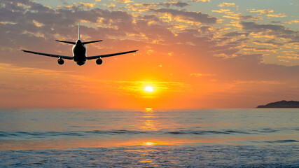 Fototapeta na wymiar Sunset or sunrise (dawn, dusk ) flight of the airplane (jet) over beautiful sky and ocean.