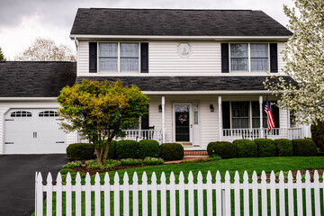 white colonial house with white picket fence and American flag