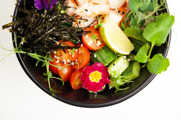 Poke salad with shrimp in a bowl. Ingredients Shrimp, blanched spinach, cherry tomatoes, rice, cucumber, soy-ginger sauce, Spicy sauce, nori, sesame, lime, cilantro. Asian seafood salad concept.