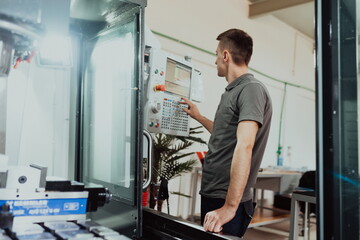 a man puts an aluminum piece on a cnc machine and prepares a processing machine..