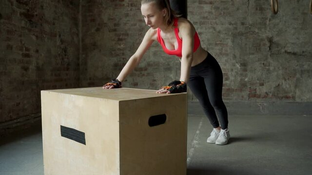 Athlete young woman does push-ups on a wooden box in the gym