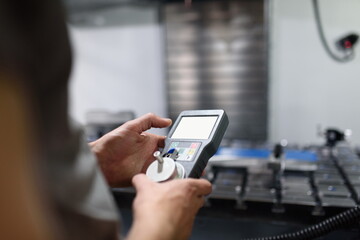 Worker entering data in CNC machine at factory floor to get the production going.