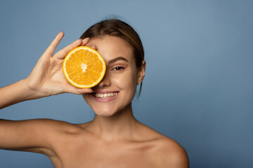Happy young woman holds citrus to her face. Vitamin c concept