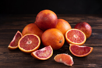 Hill of juicy fresh blood orange on a dark wooden background, healthy food, rustic style.