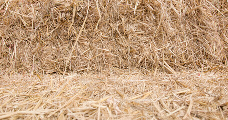 Hay bales are stacked in large stacks for wallpaper or background.