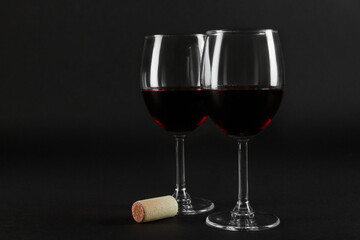 Two glass glasses of red wine on a black homogeneous background