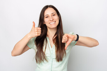 A photo of a young smiling woman showing a like and a dislike sign while she is looking at the...
