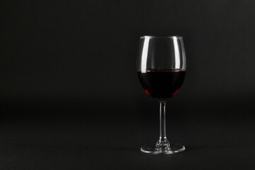 One glass goblet of red wine on black homogeneous background